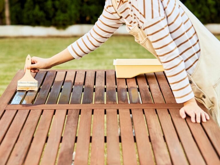 Woman staining a slatted outdoor wood table