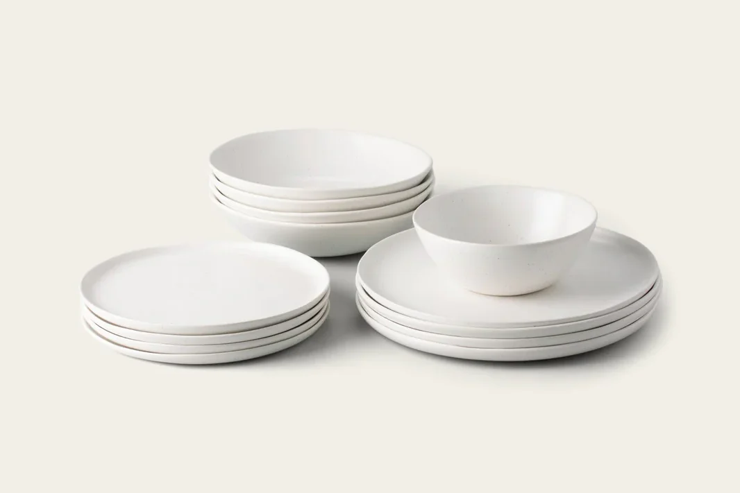White minimalist dinnerware set stacked on a neutral background.