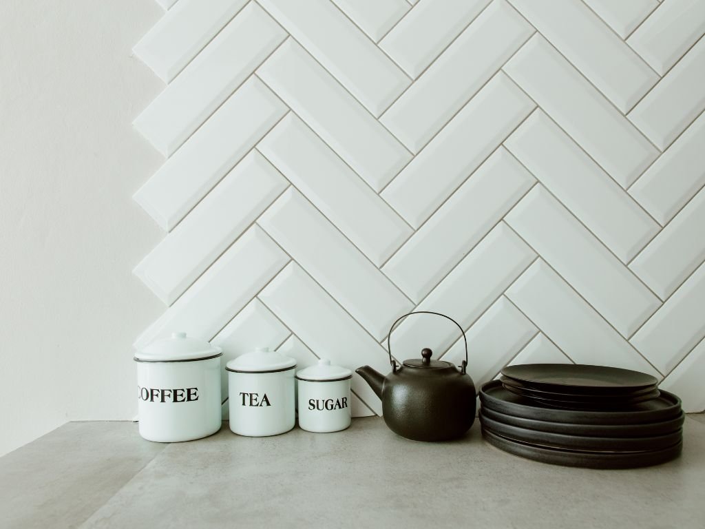 White tea canisters on a herringbone backsplash