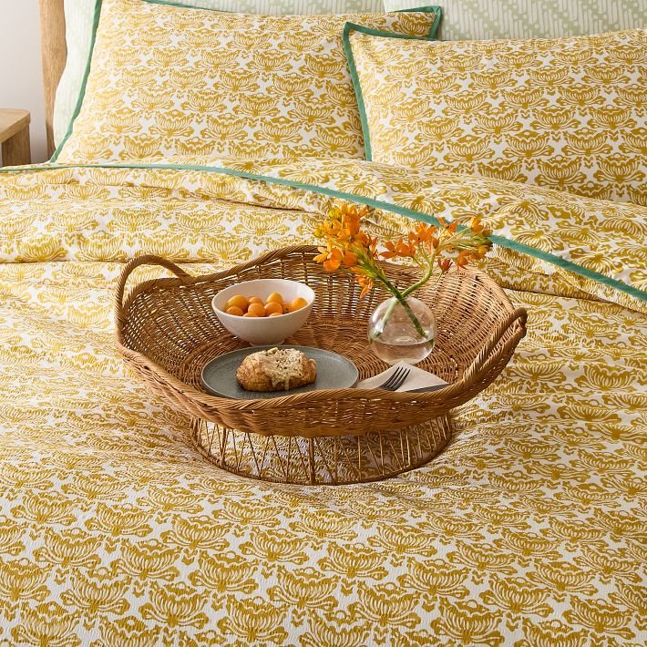 Wicker tray with breakfast items on a summer bedspread