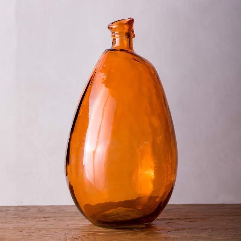 Amber recycled glass vase on a table, blending sustainable style with eco-friendly materials.