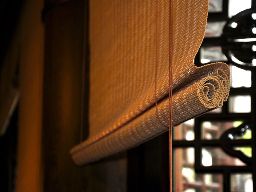 Rolled bamboo roman shades on a window