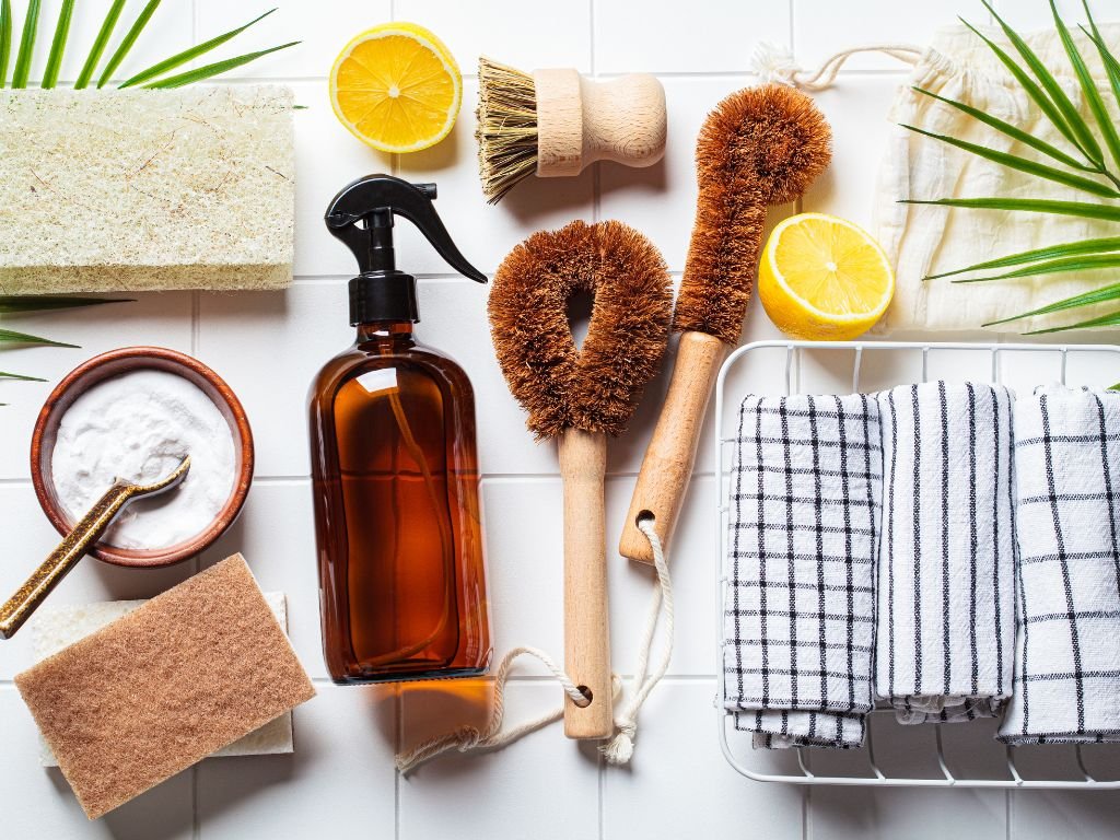 Natural cleaning brushes and glass spray bottles on white counter