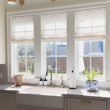 Neutral linen Roman shades in bright kitchen window