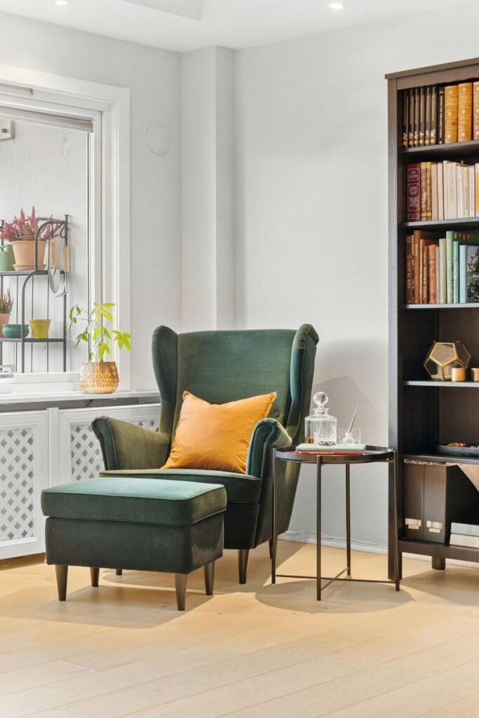 Green accent chair with side table and bookshelves.