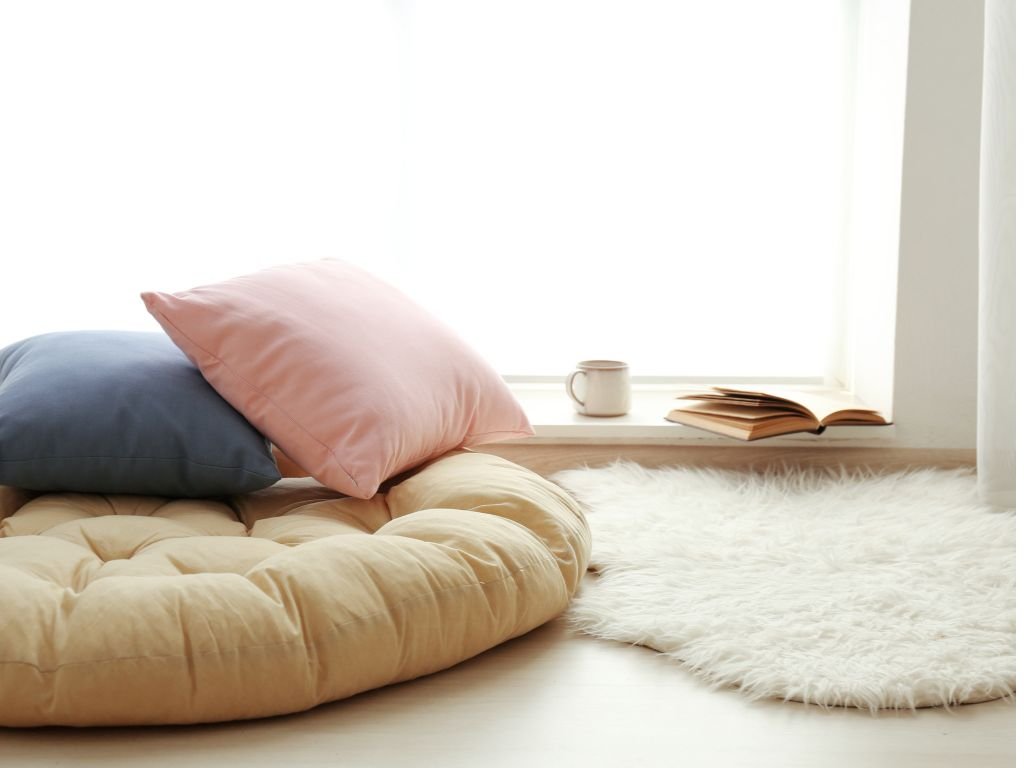 Window ledge with cushions and soft mat in neutral tones.