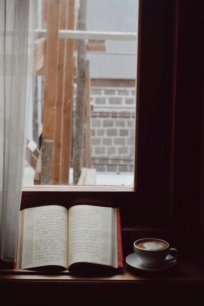 Open book and coffee cup on window ledge