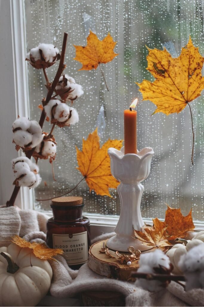 Candle with autumn leaves on rainy window