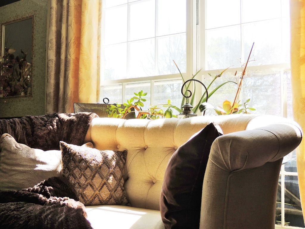 Window nook with layered cushions and soft lighting for reading.