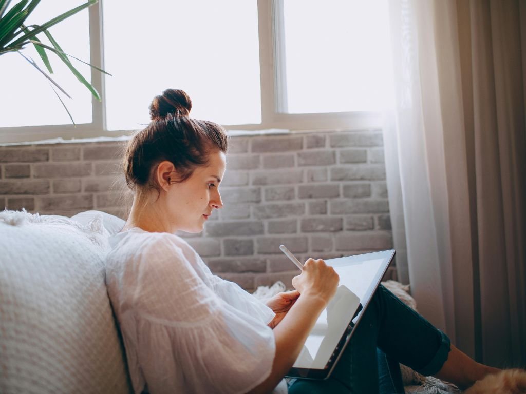Person reading by a bright window with soft blanket.